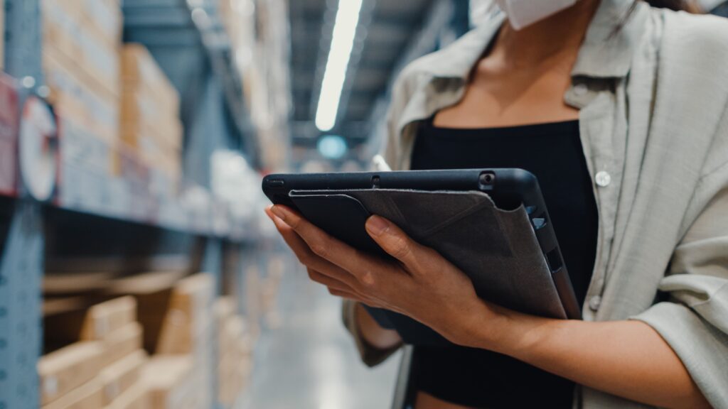 Gestion des stocks dans un entrepôt logistique e-commerce Employée en entrepôt logistique vérifiant les stocks sur une tablette