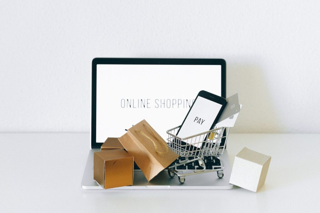Ordinateur affichant “Shop online” avec des sacs et cadeaux représentant l’achat en ligne